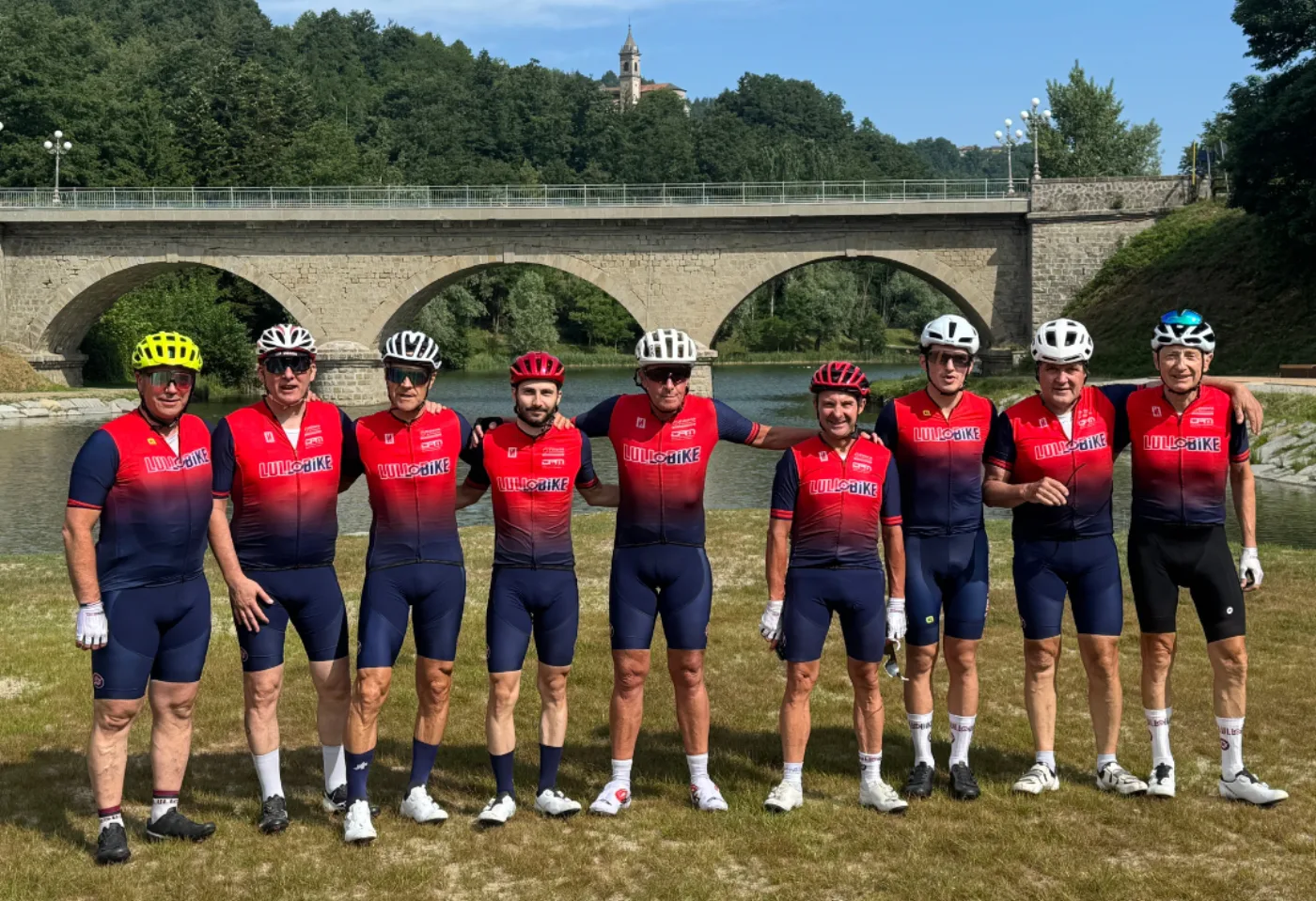 Il Team Lullobike in maglia sociale davanti a un ponte in pietra